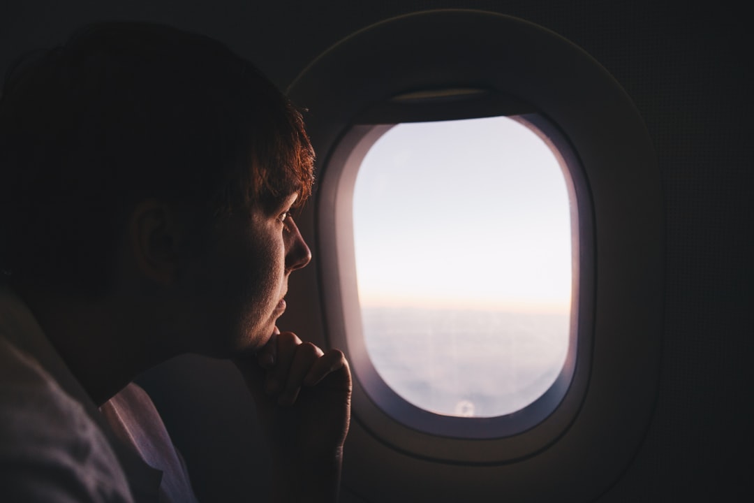 Passager accoudé au hublot dans une cabine plongée dans la pénombre